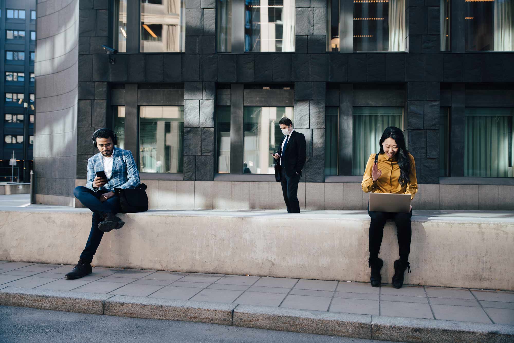 En kvinna på sin dator och en man på sin mobil utomhus